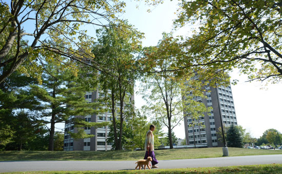 Women walking with her dog in front of apartment buildings