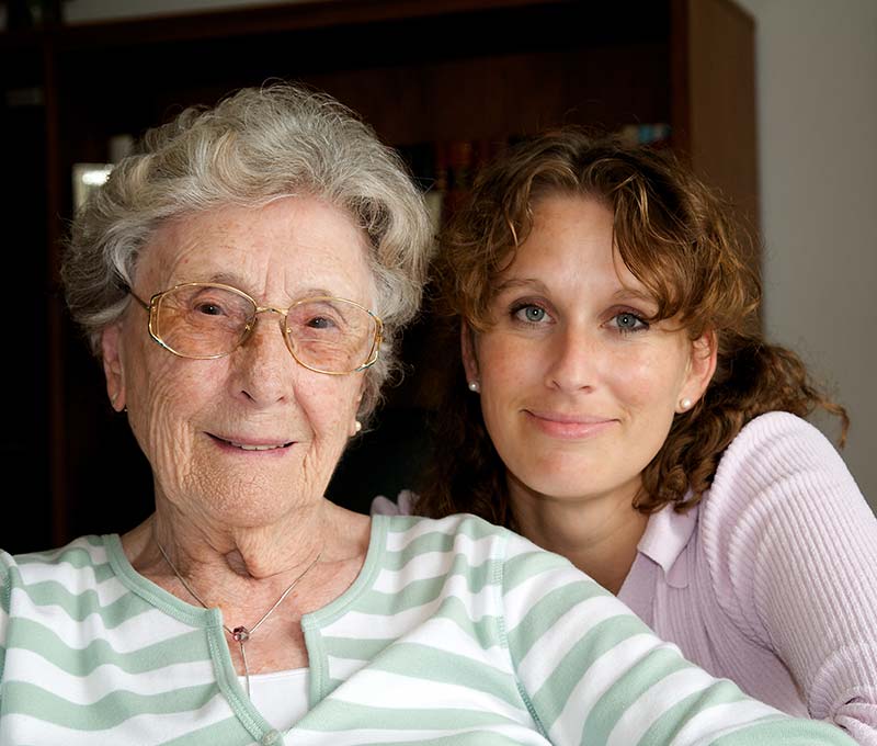 an elderly woman with glasses sitting inside with her daughter