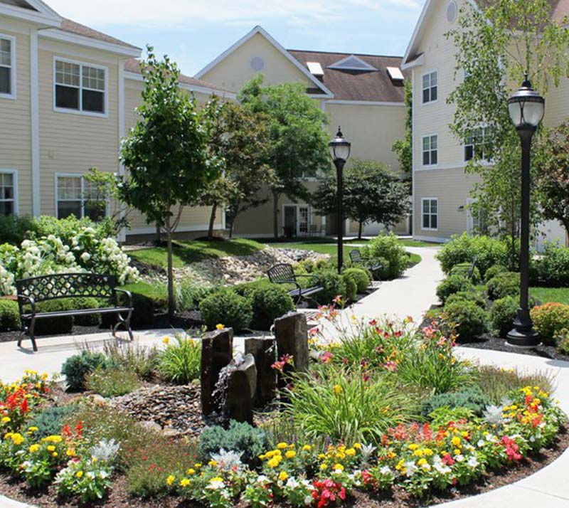 water fountain, landscaping, benches and walkways outside of the Woodlawn Commons retirement community