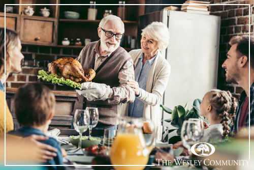 grandpa with delicious turkey for thanksgiving dinner with happy family