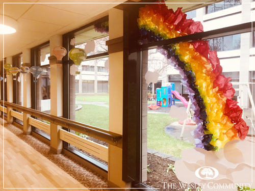 A handmade rainbow displayed on a window.