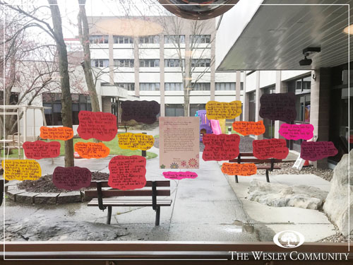 Written notes on colorful paper hanging on a window.