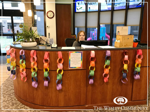A woman sitting at a reception desk that is decorated with rainbows.