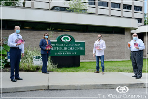 A group of four people posing infront of Wesley Health Care Center.