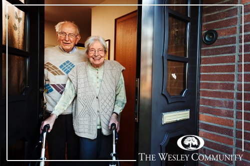 A senior couple answering the door at their home.