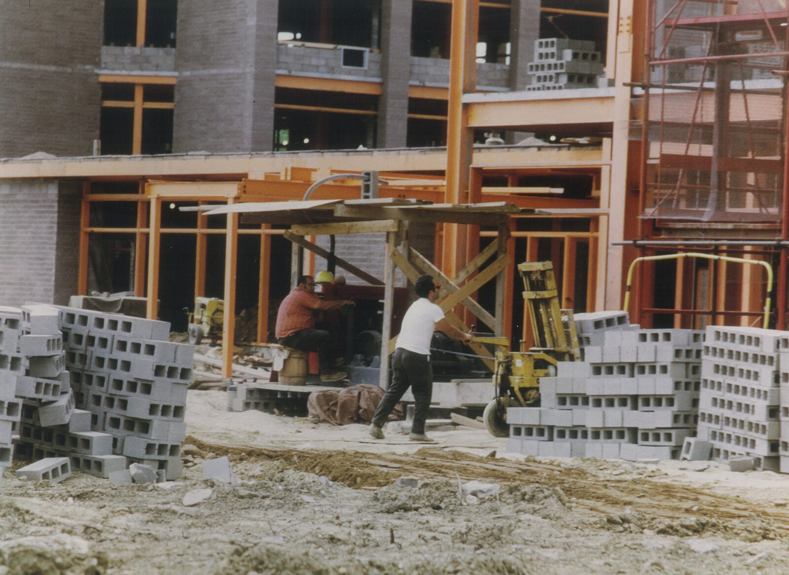 Photograph of steel framing for Embury Apartments with workers and concrete