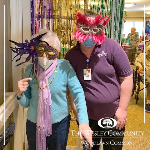 A senior and her aide in Mardis Gras Masks.